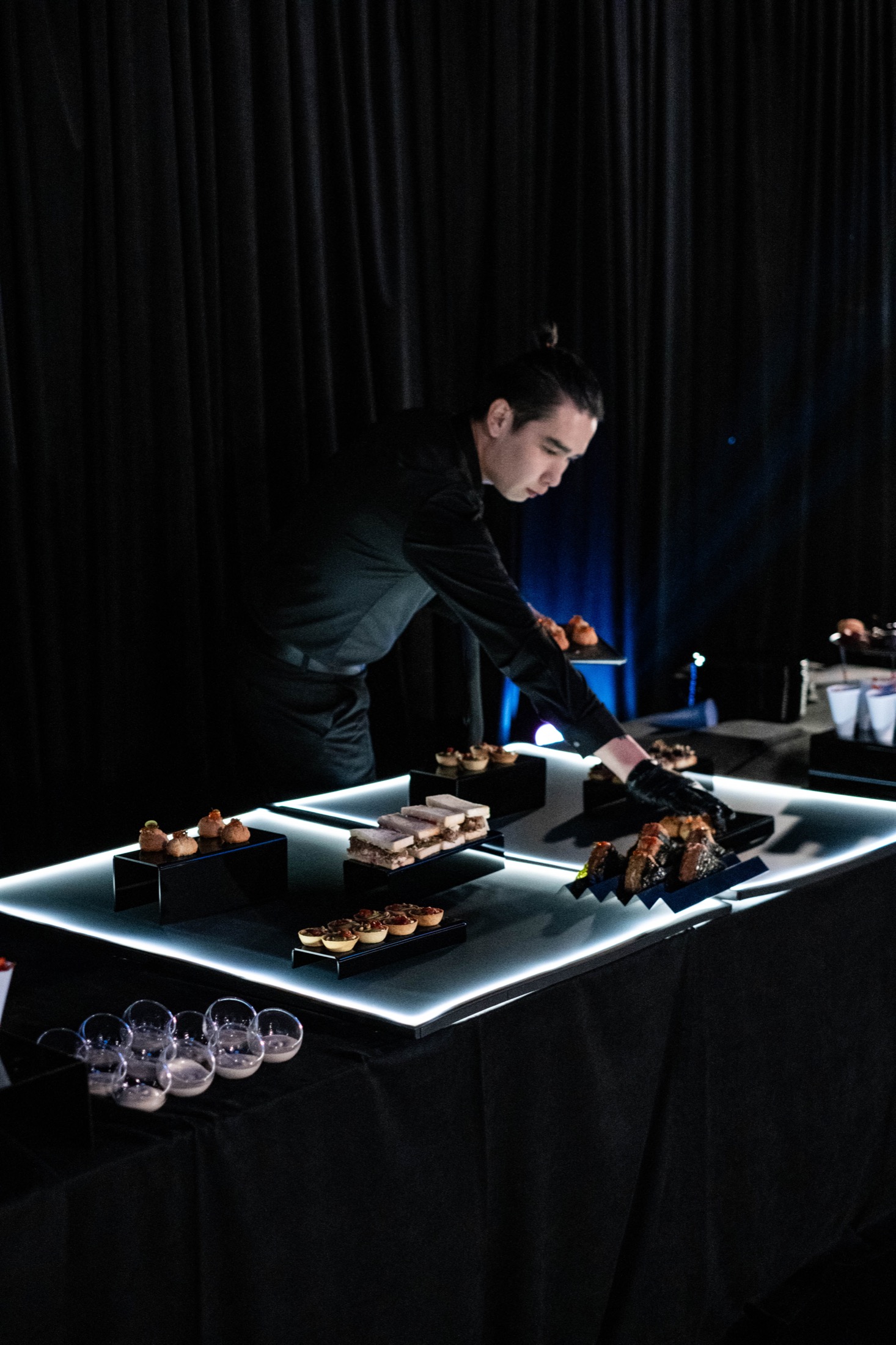 Команда Good Catering расставляет блюда на световом сервисном столе