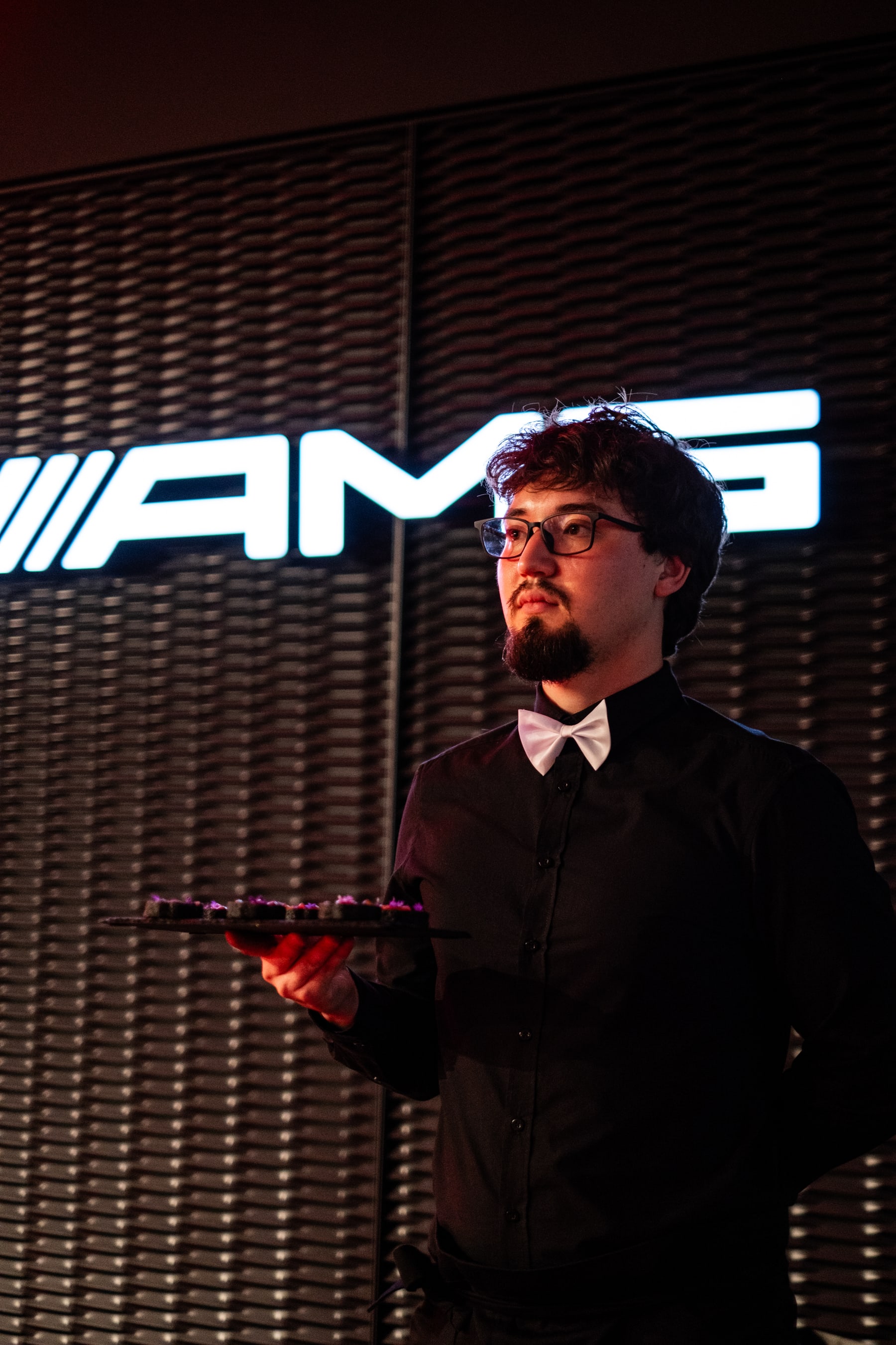 Service team presenting dishes in front of an AMG sign