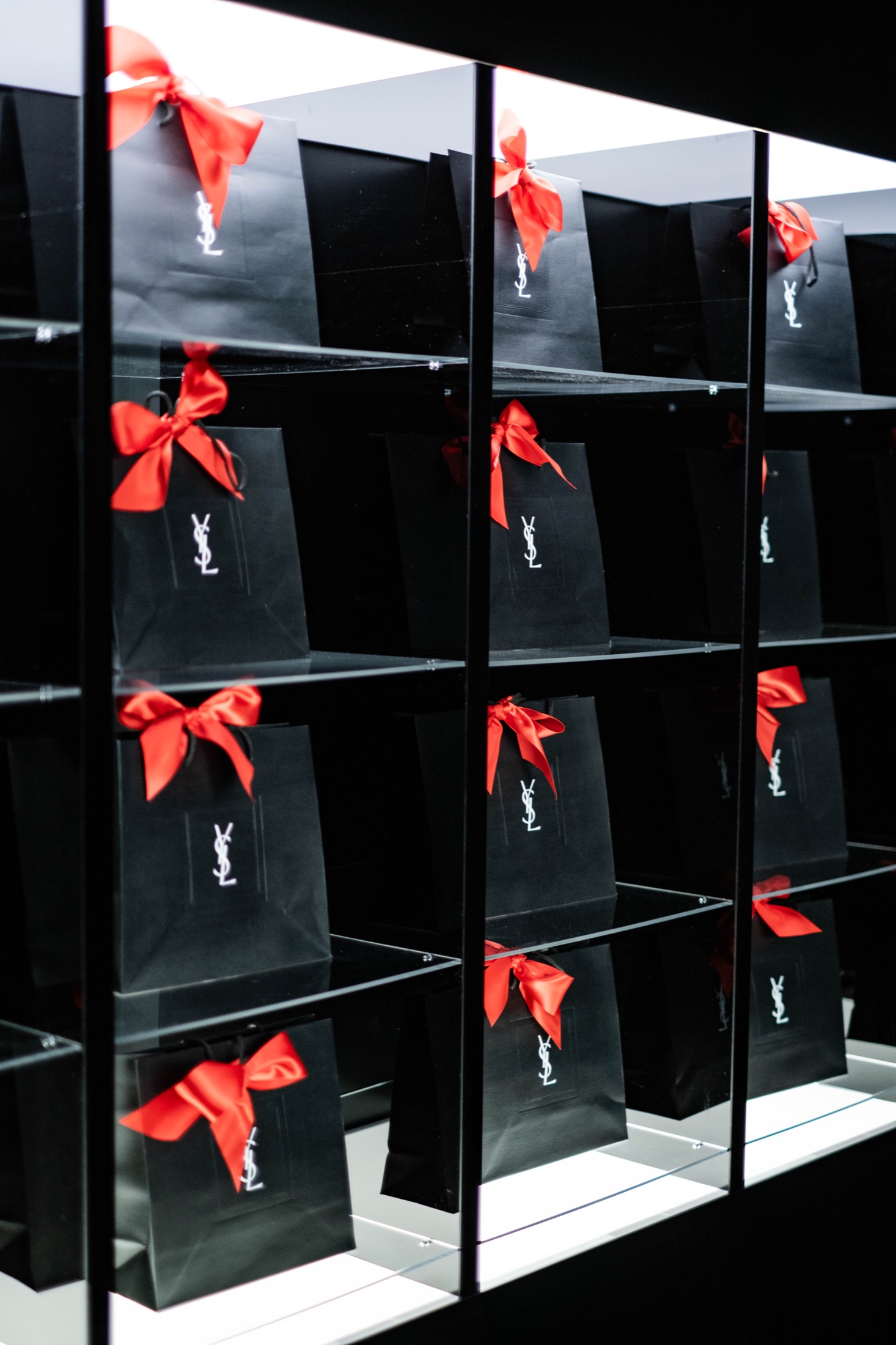 Подарочные пакеты YSL с красными бантами в подсвеченной витрине
